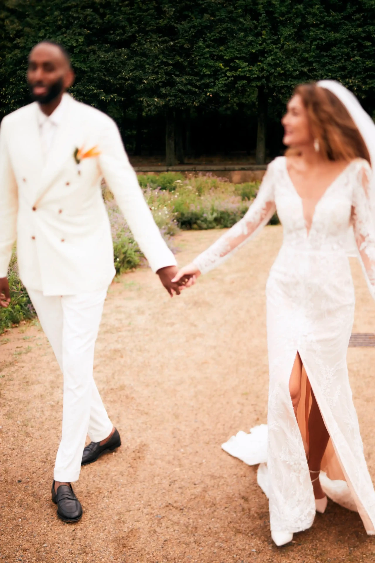 Bride and groom laughing and holding hands in a garden