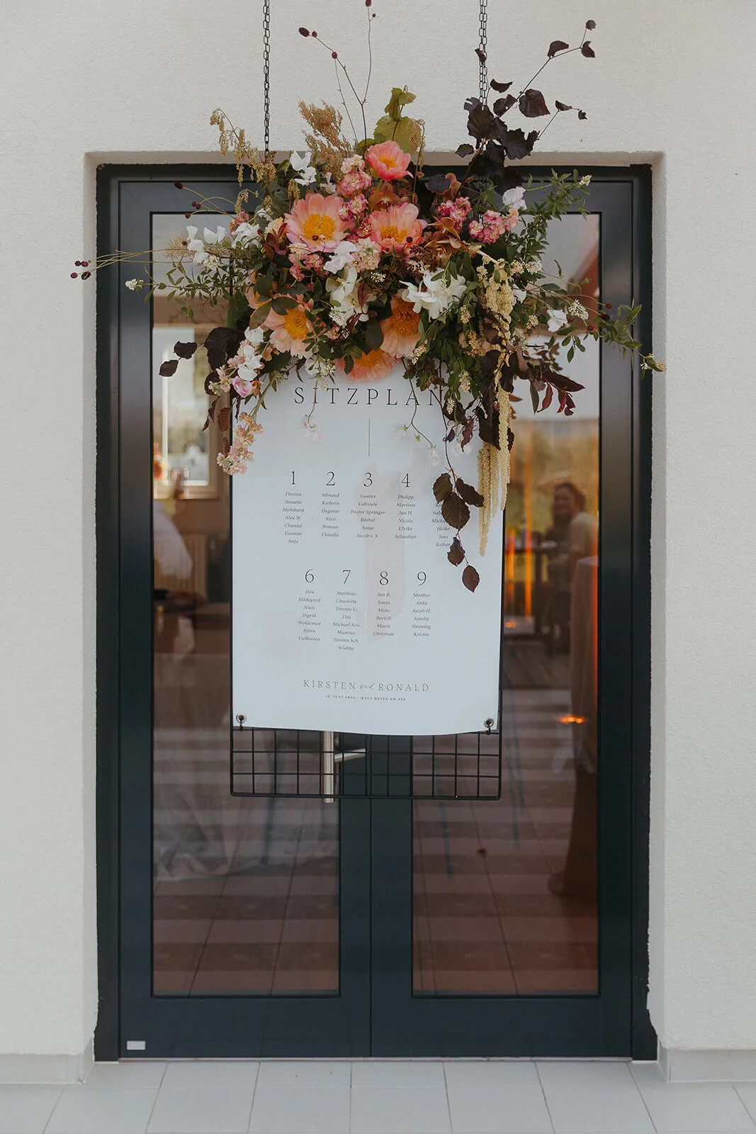 Wedding card on a door beside floral decoration