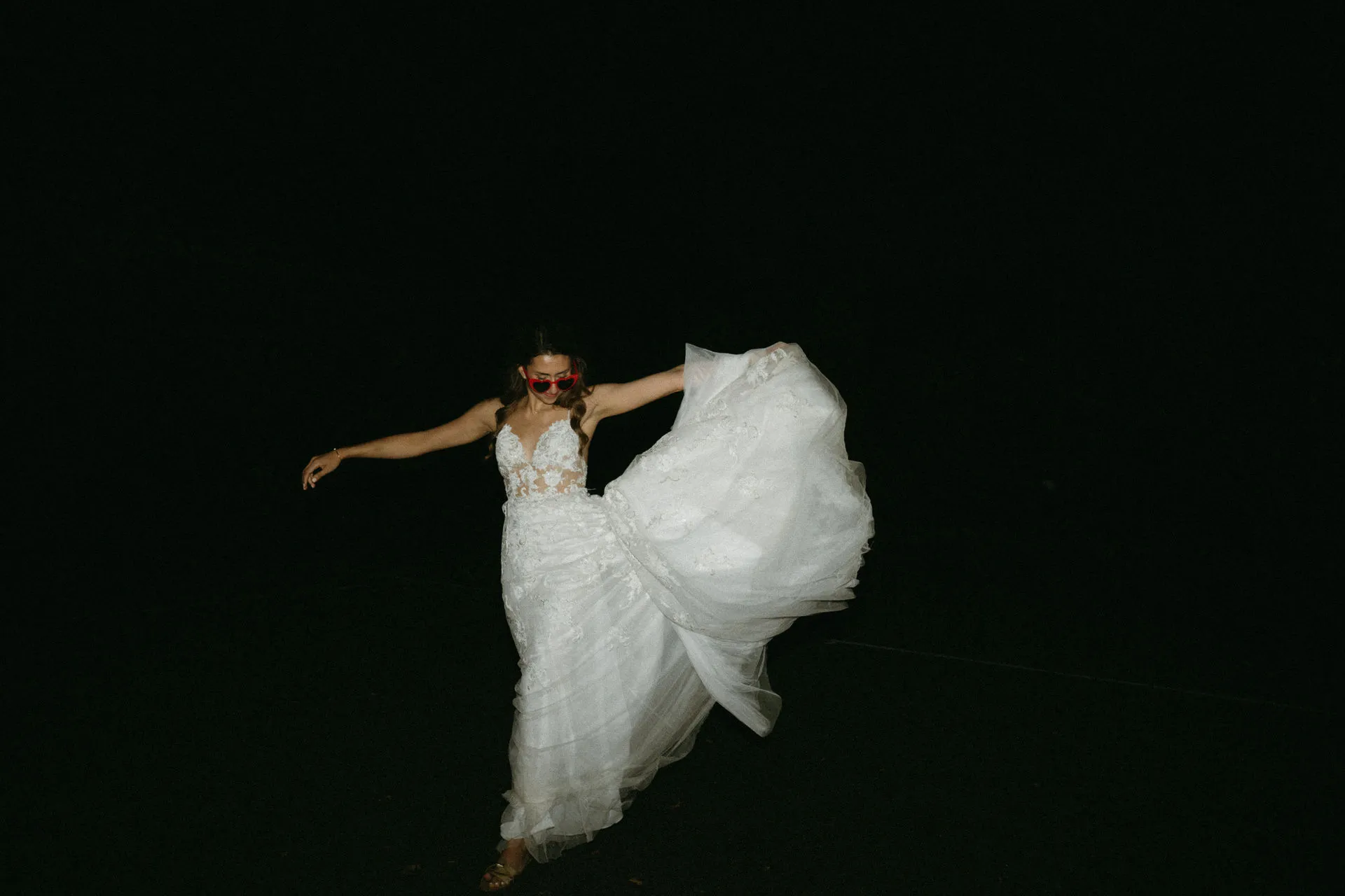Bride tossing her veil into the air against a dark background