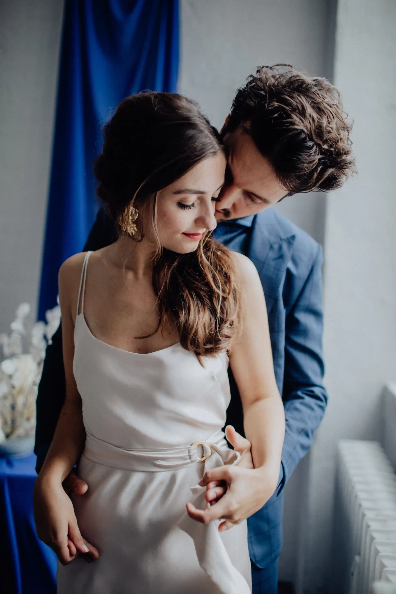 Wedding couple standing close together, the bride wearing a simple white dress
