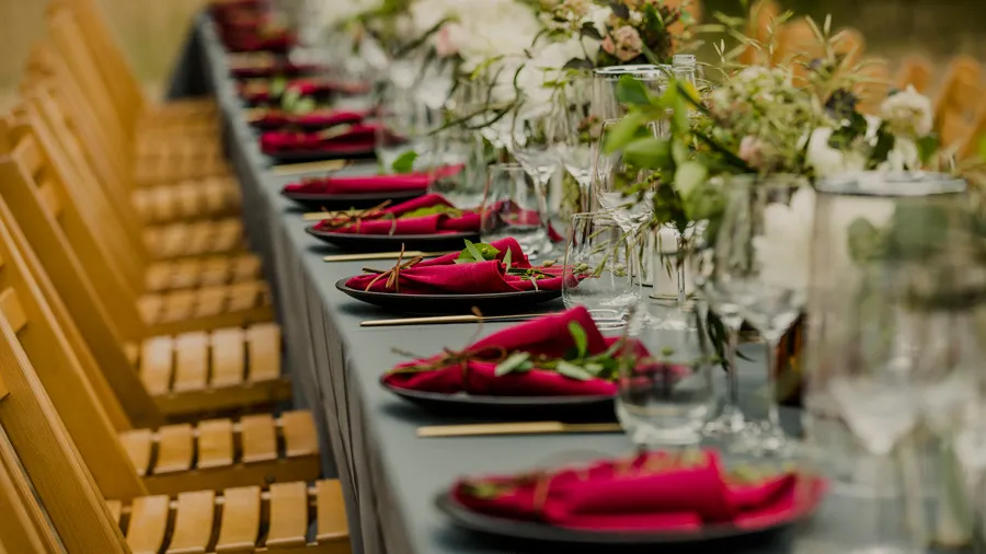 Long wedding table with red napkins and floral decorations