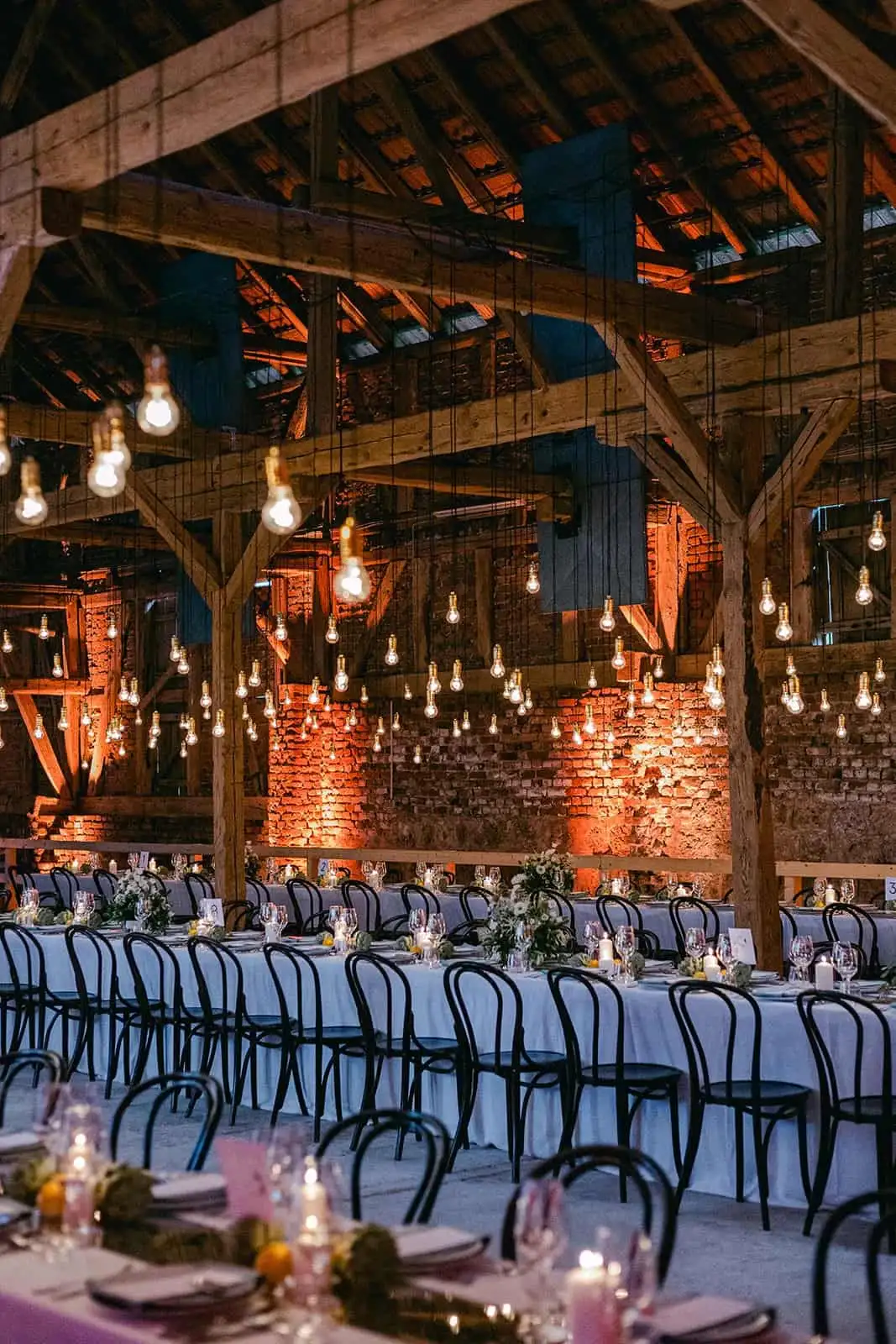 Wedding tables in a rustic barn with hanging light bulbs