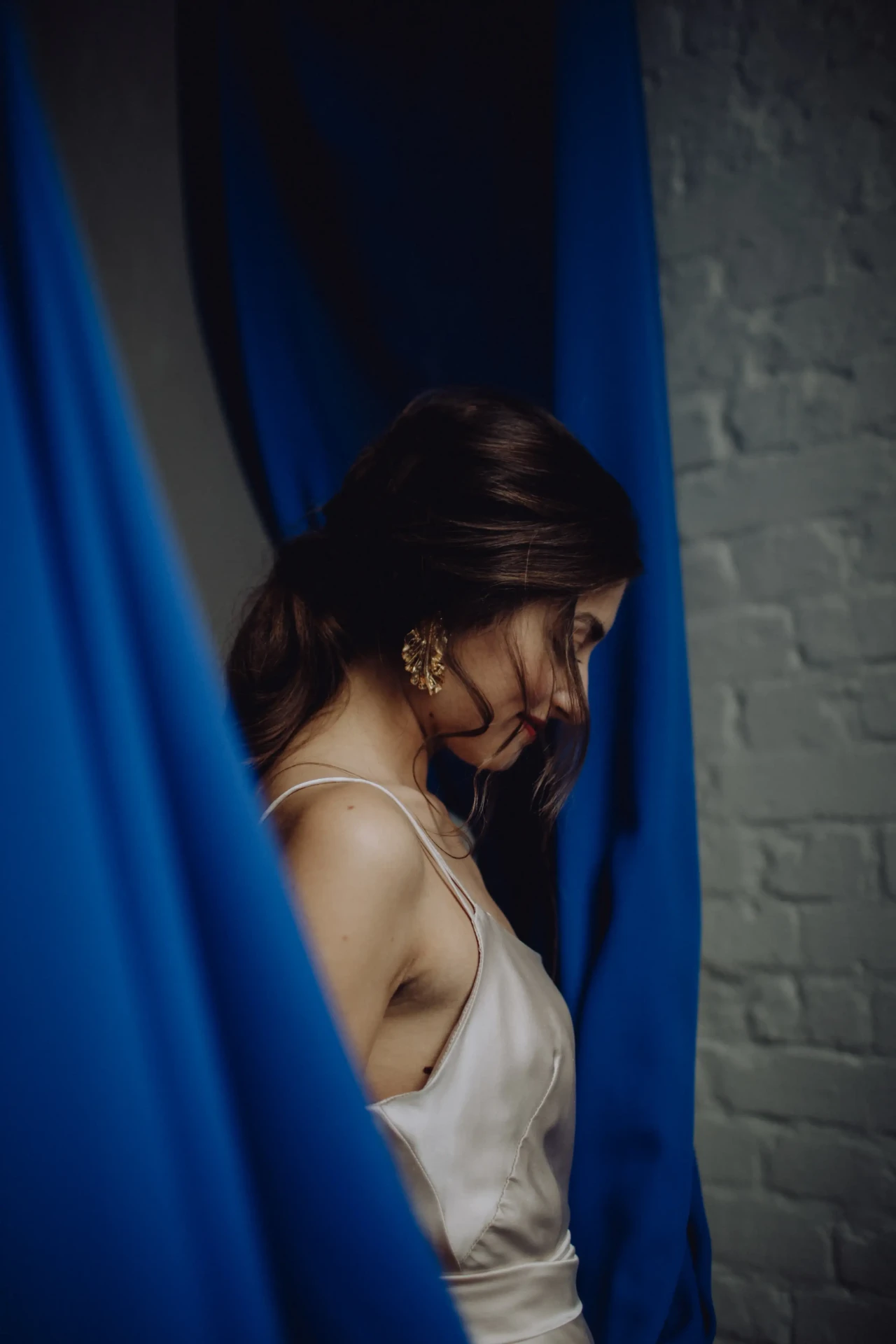 Bride wearing a veil in front of a blue curtain, head lowered