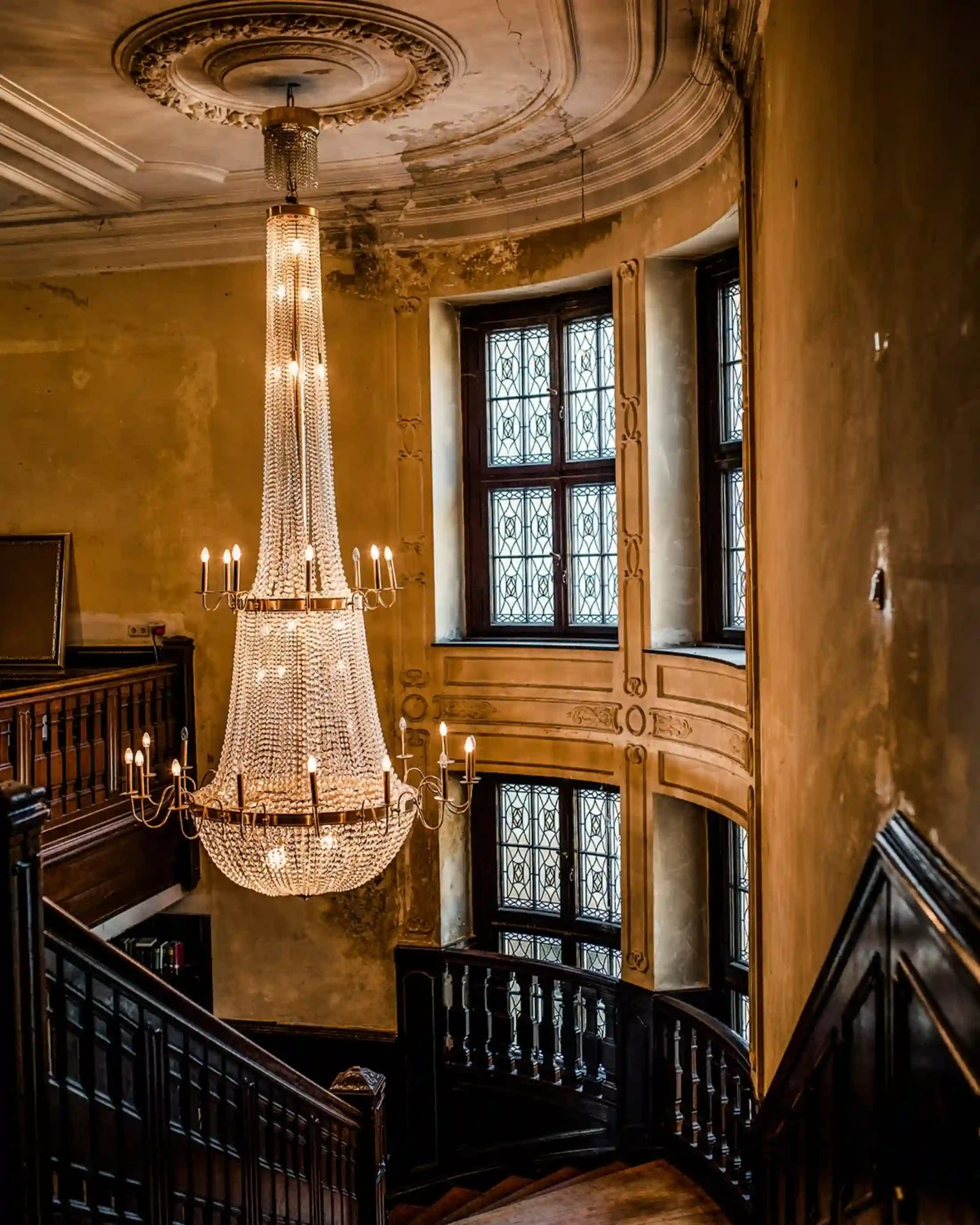 Historic interior with a large chandelier and sweeping staircase