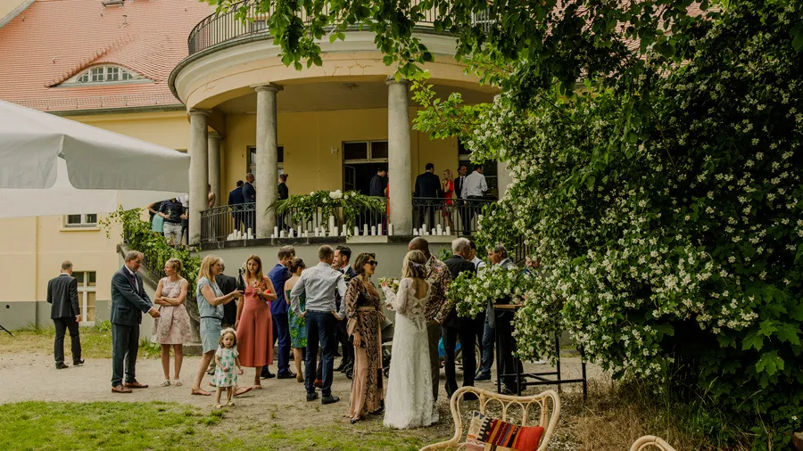 Wedding guests gathered in front of a villa in the garden