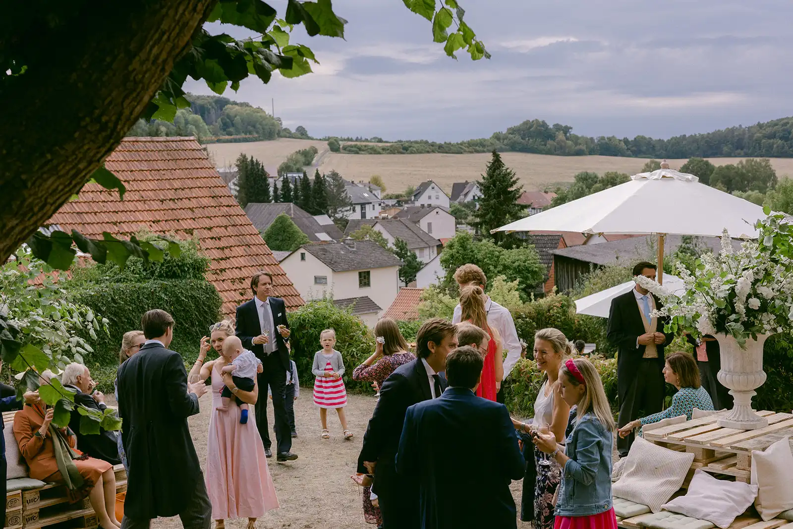 Wedding guests gathered on the estate among trees and white marquees