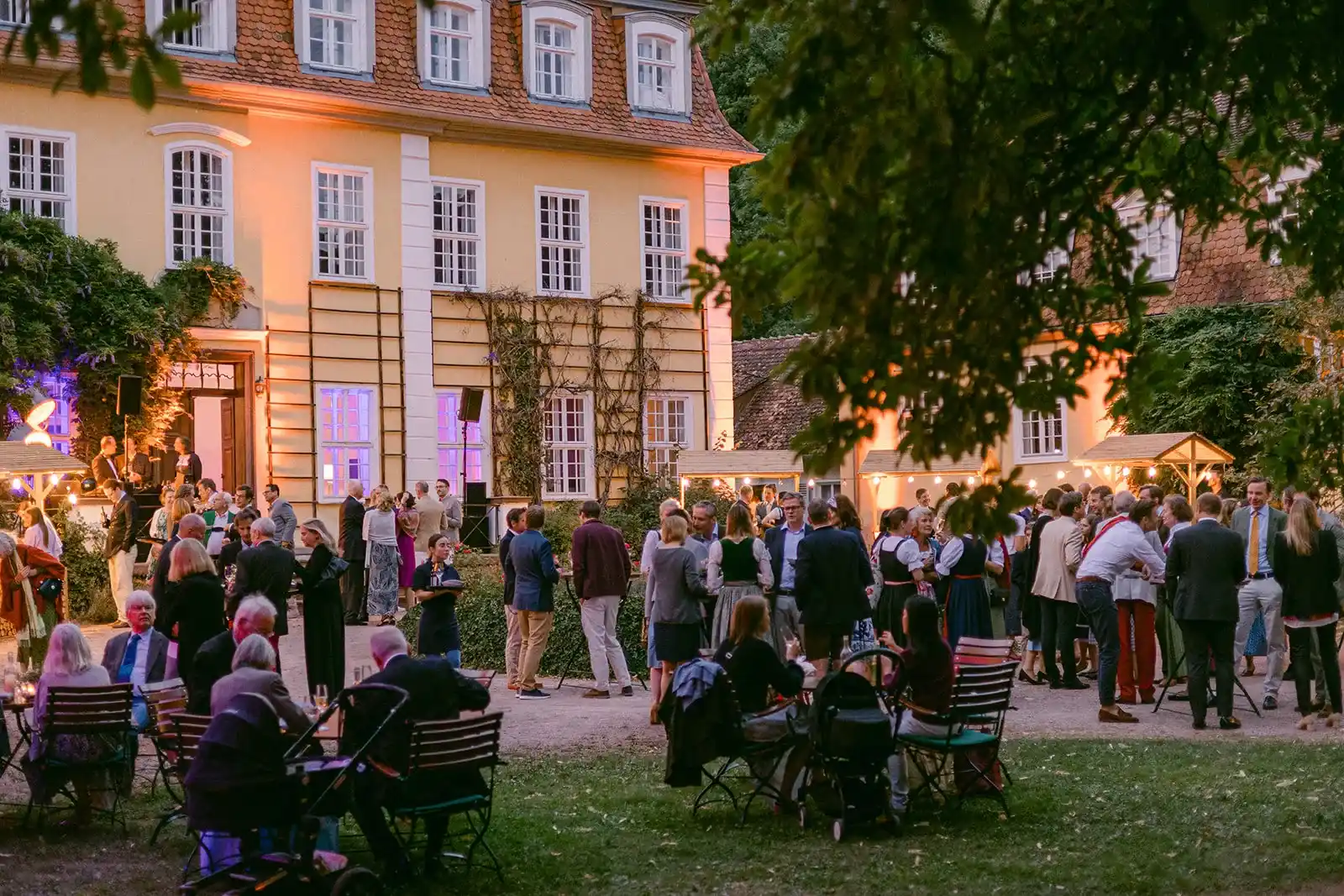 Wedding guests gathered in front of a country house in the evening