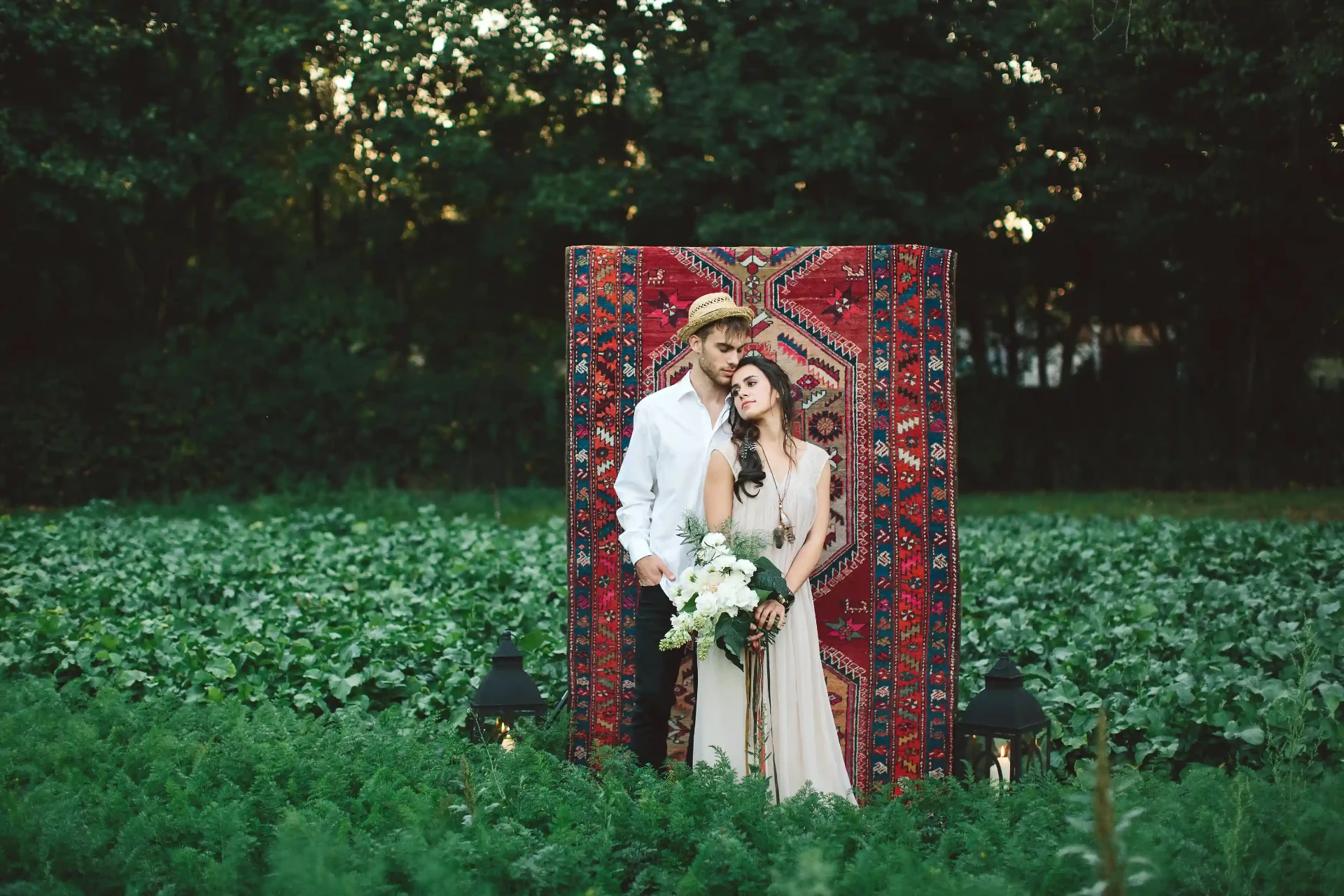 Wedding couple standing in front of a red rug in a meadow