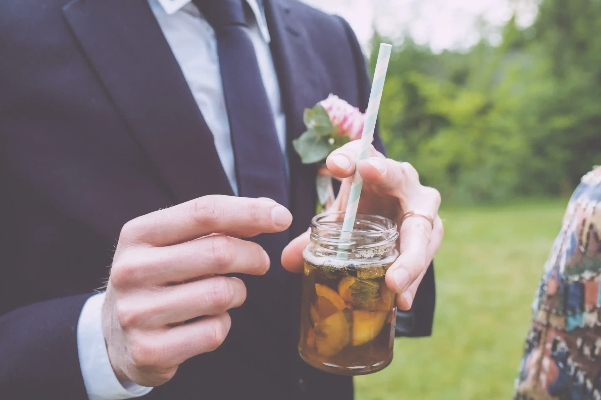 Groom holding a small glass or bottle of a drink