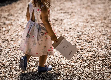 Woman in a pink dress walking along a gravel path