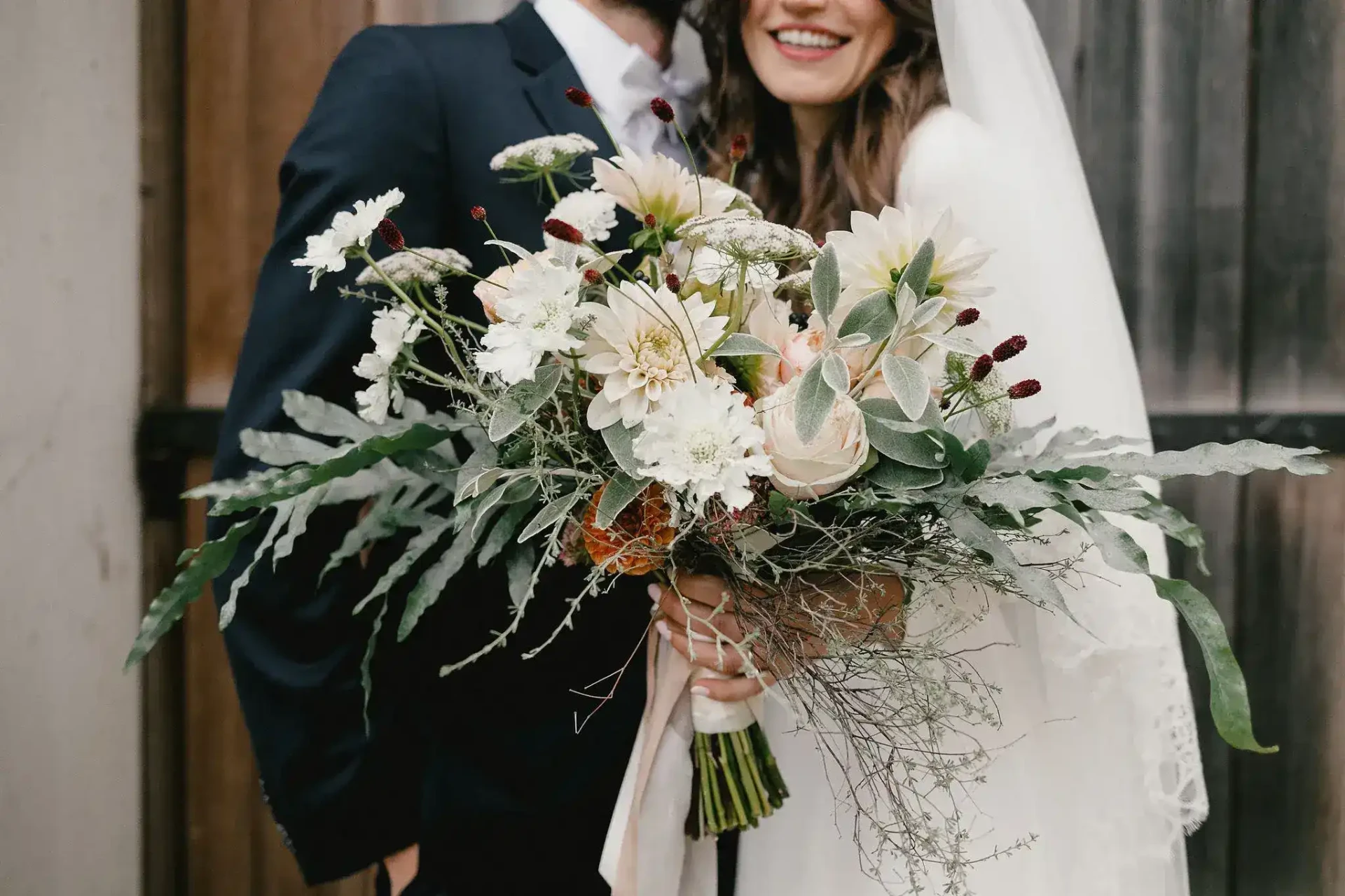 Bride holding a large bouquet in front of her dress
