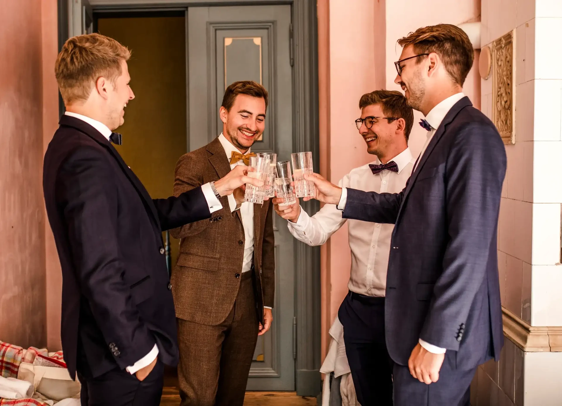 Groom and two guests raising their glasses indoors