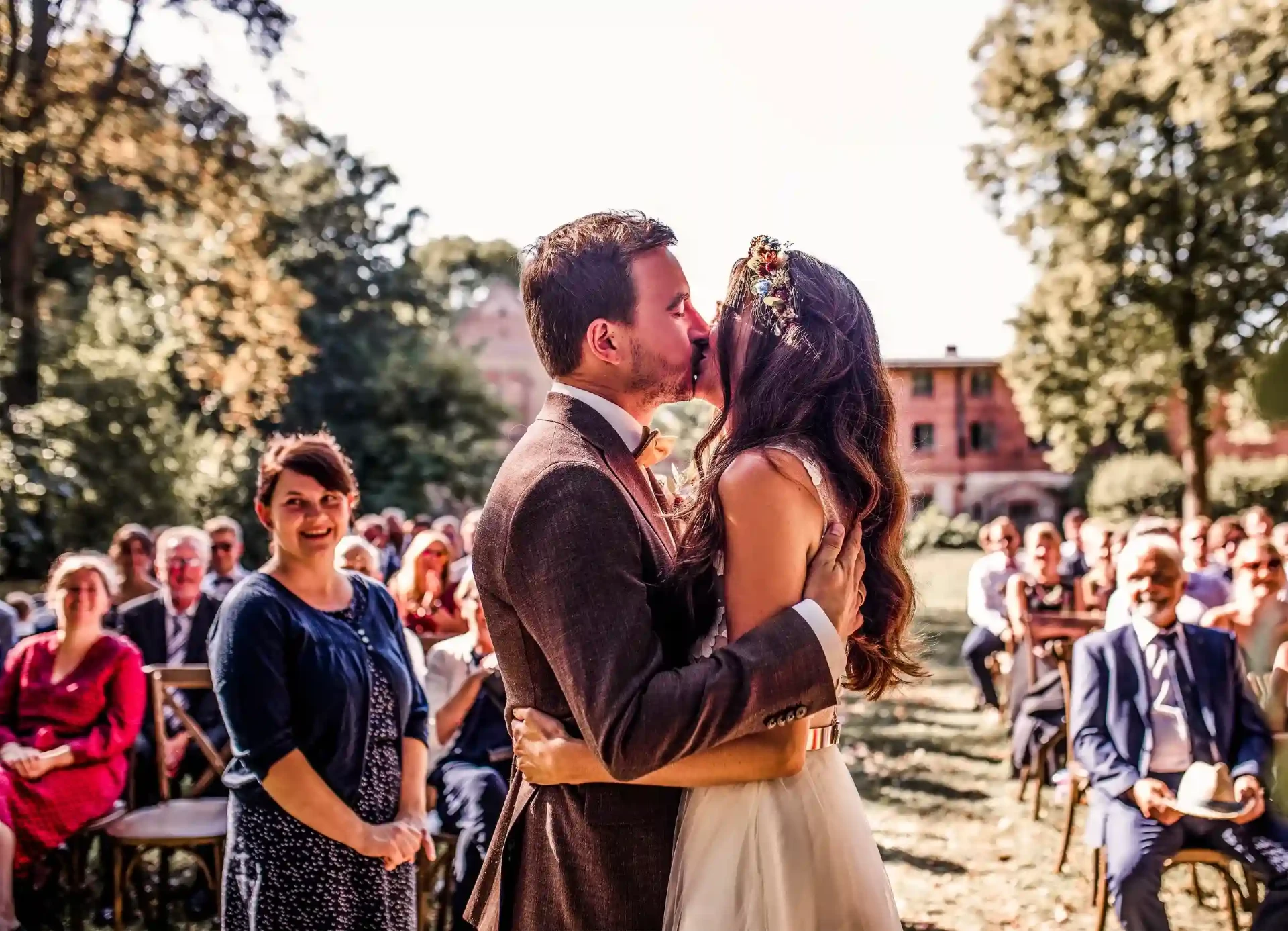 Bride and groom kissing in front of cheering wedding guests