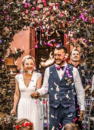 Bride and groom standing in front of a flowering wall