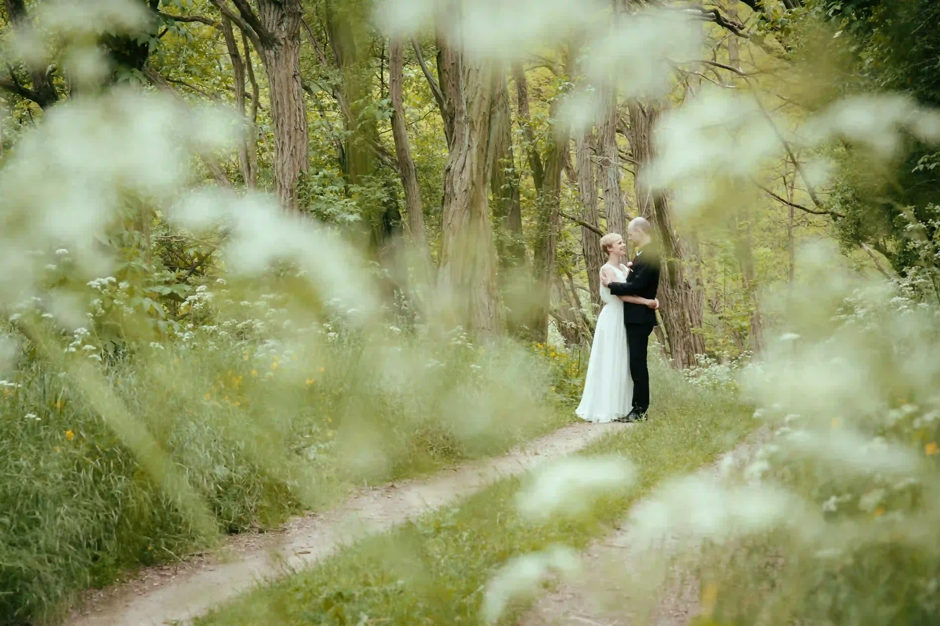 Bride standing on a narrow path among trees and tall grass