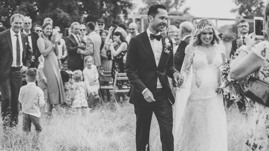 Bride and groom walking with guests across a meadow