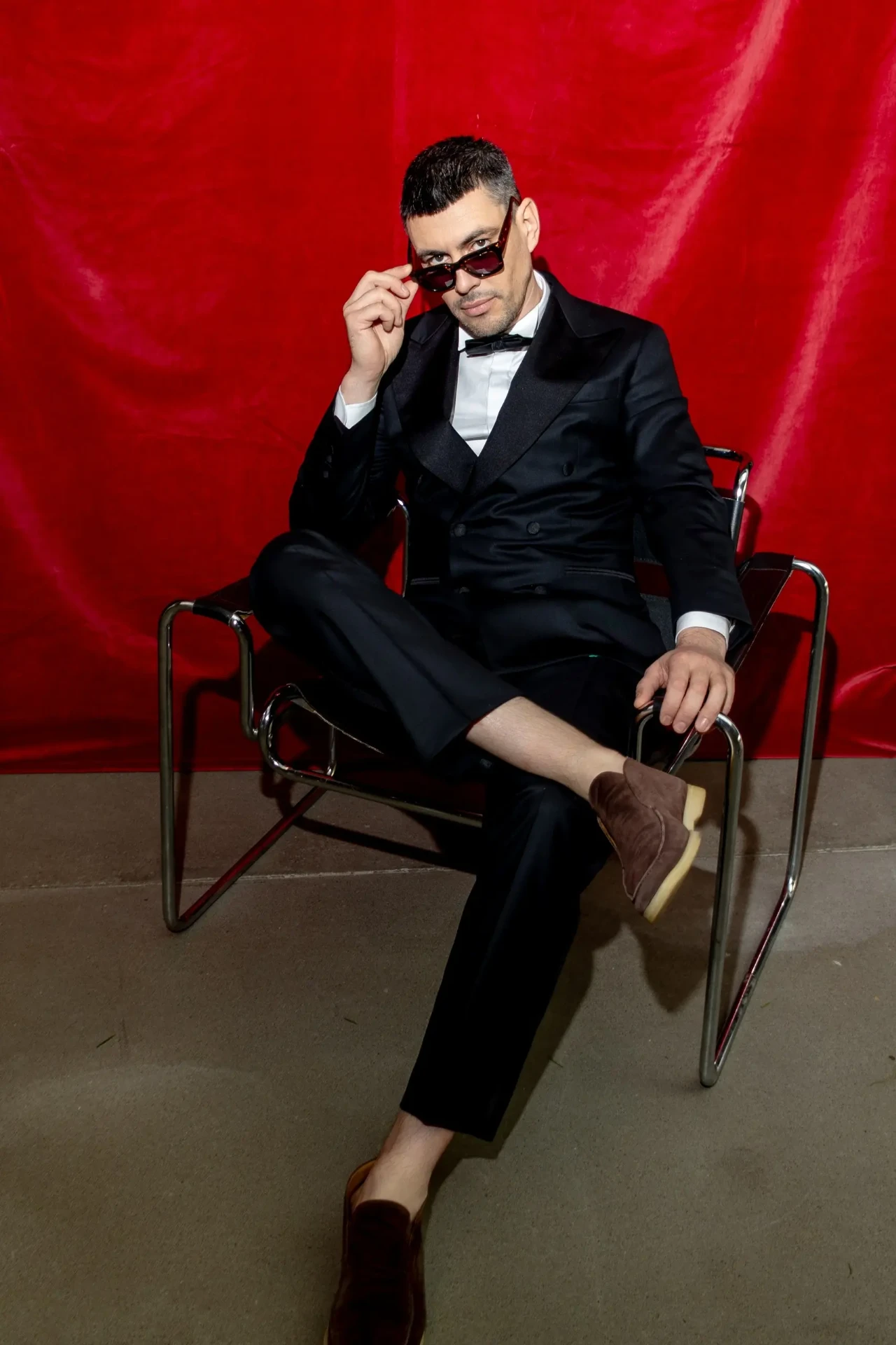 Man in a suit seated in front of a red backdrop