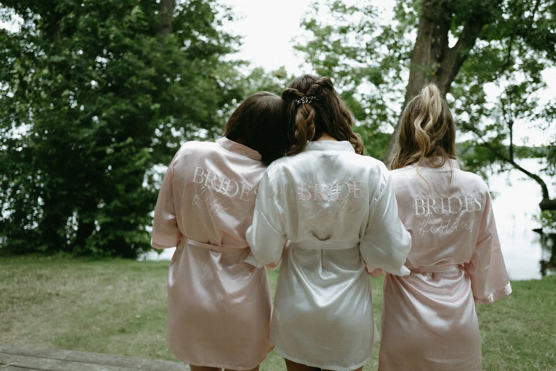 Three wedding guests in light outfits walking together through the garden