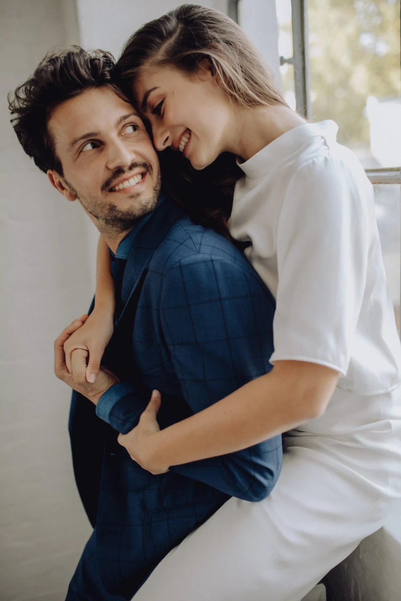 Wedding couple embracing against a light background