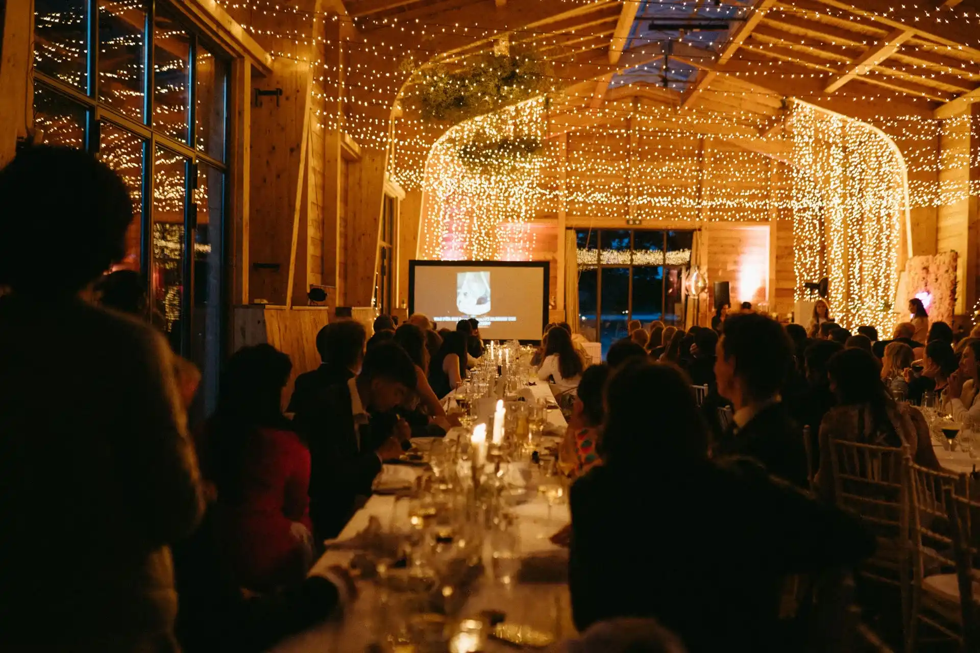 Warmly lit wedding table in a barn with hanging lights