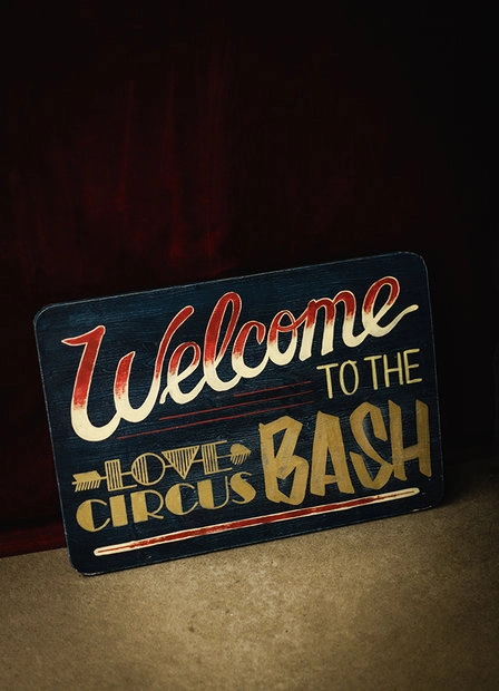 Sign reading “Welcome to the Love Circus BASH” against a dark background