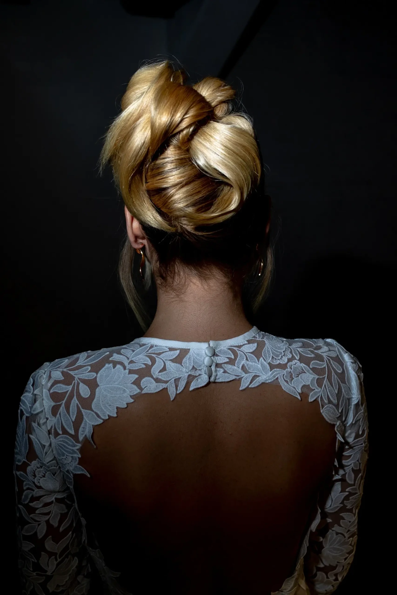 Back view of a bride in a lace dress against a dark background