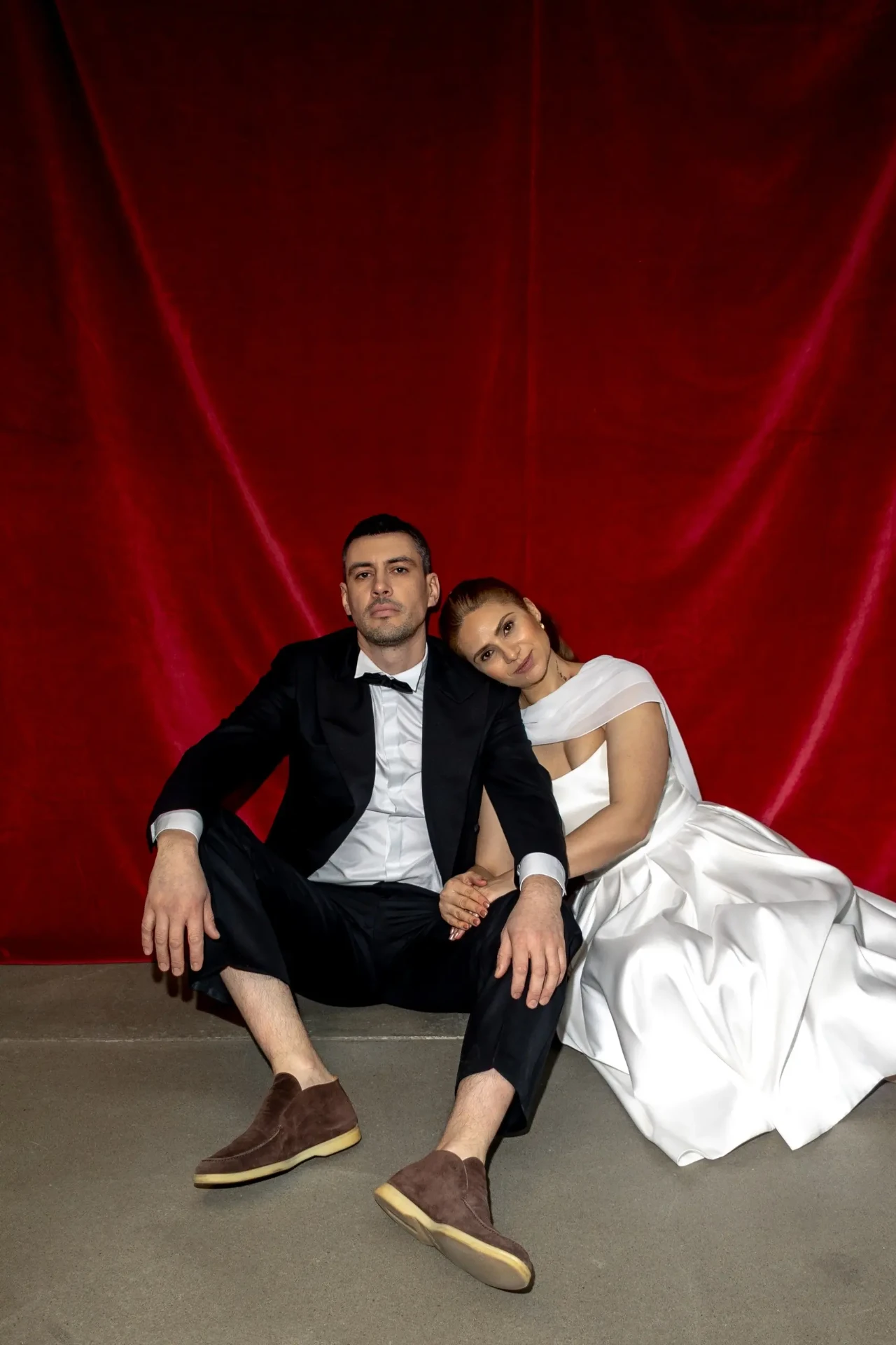 Wedding couple seated in front of a red backdrop