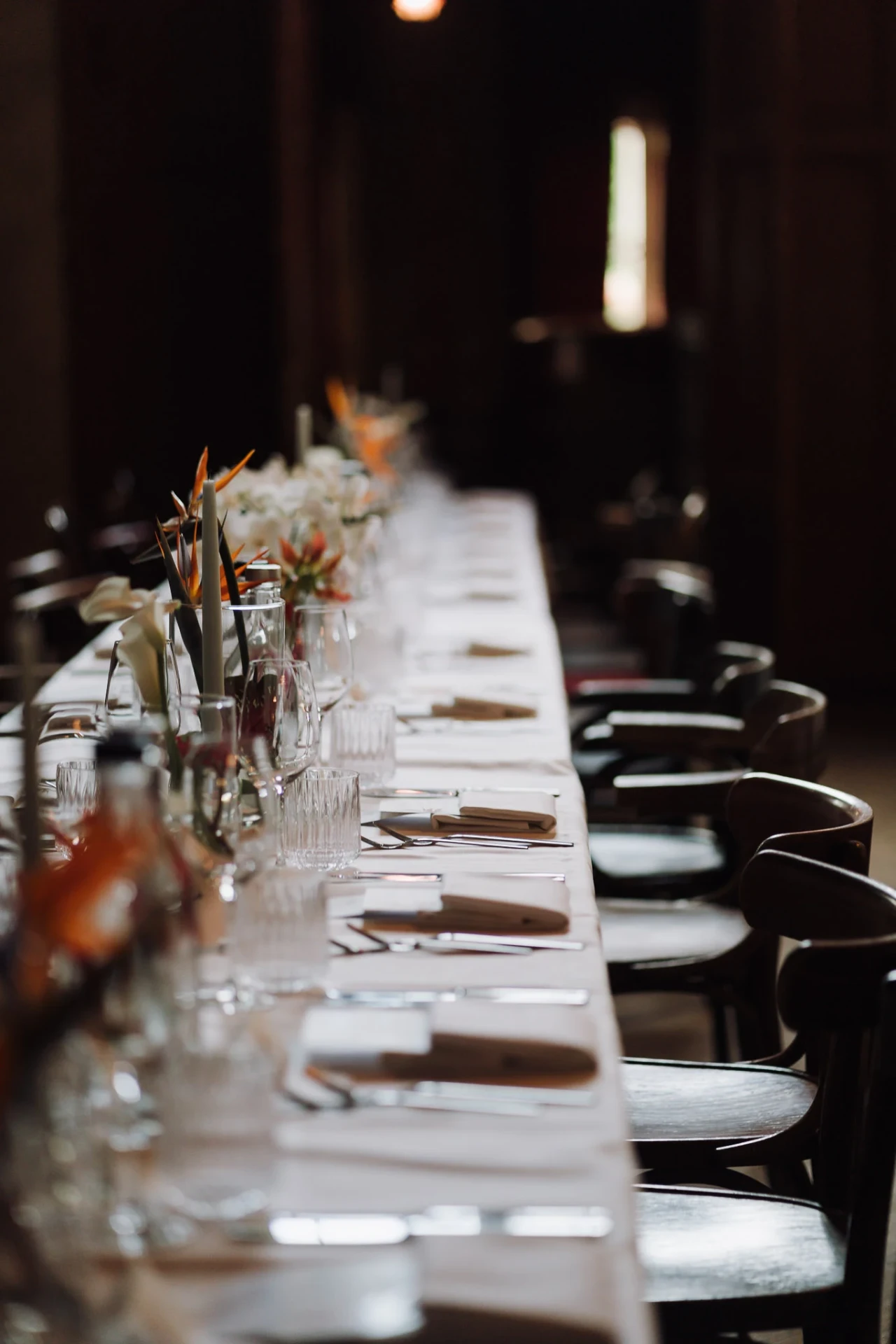Long wedding table with white chairs and warm candlelight