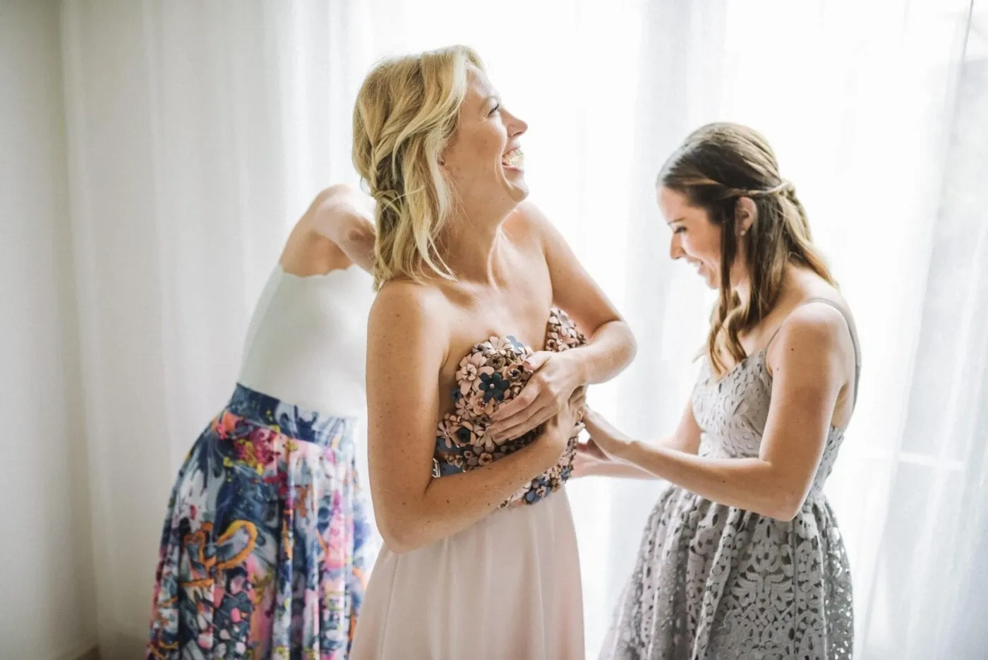 Bride being helped into her wedding dress by another woman