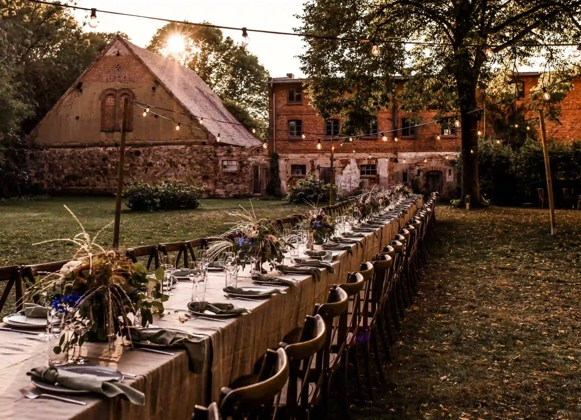 Long wedding table in a garden in front of a historic brick building
