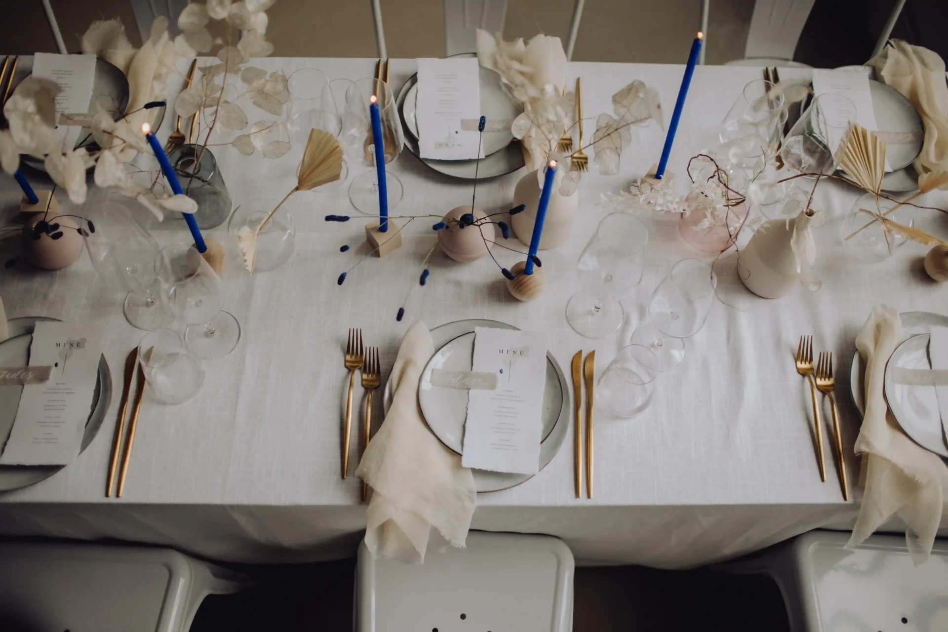 Long white wedding table with blue candles and minimalist decorations