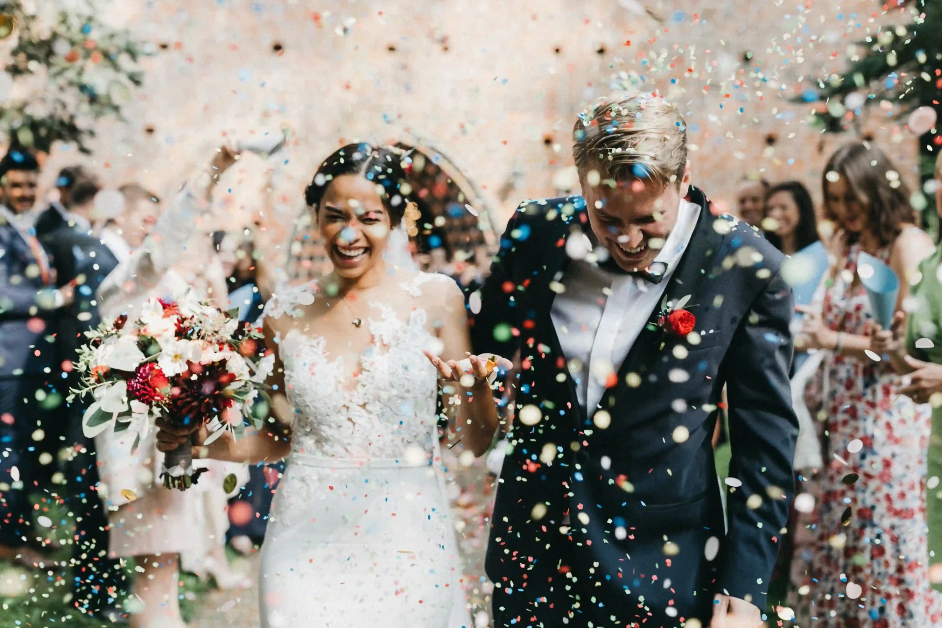 Laughing bride and groom celebrating as confetti falls around them