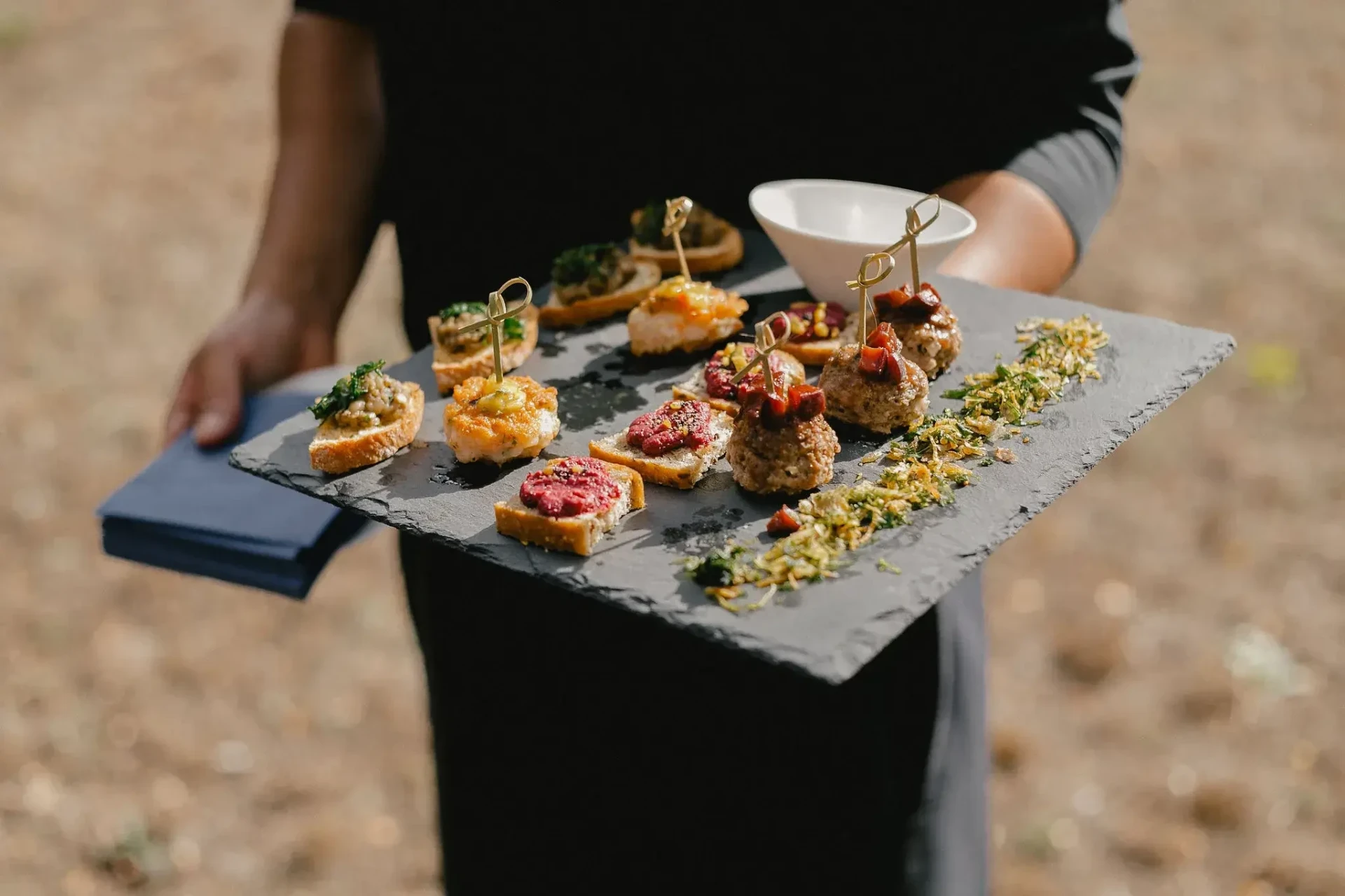 Server carrying a tray of small bites