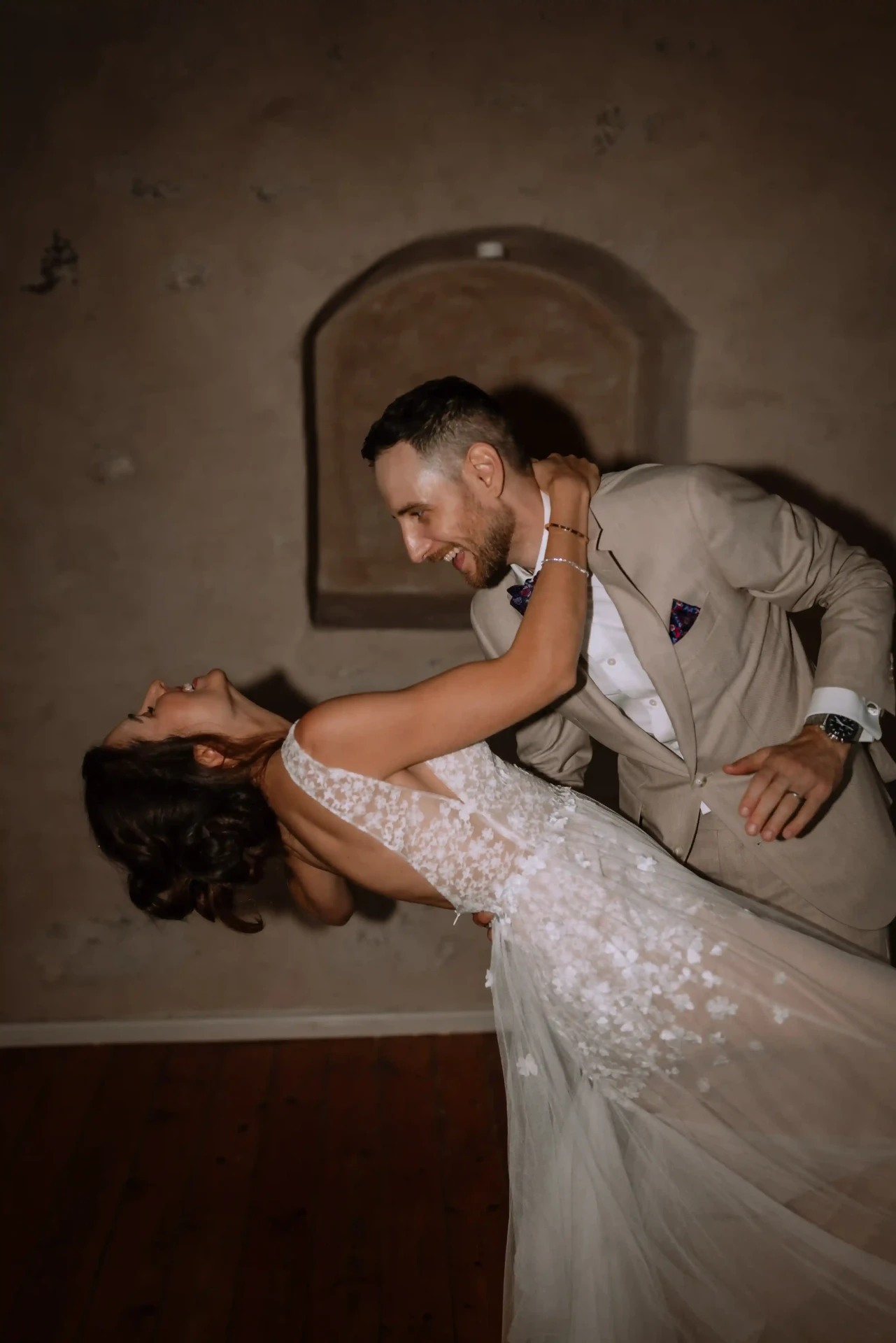 Groom smiling as he leans toward his bride, who dips back in his arms