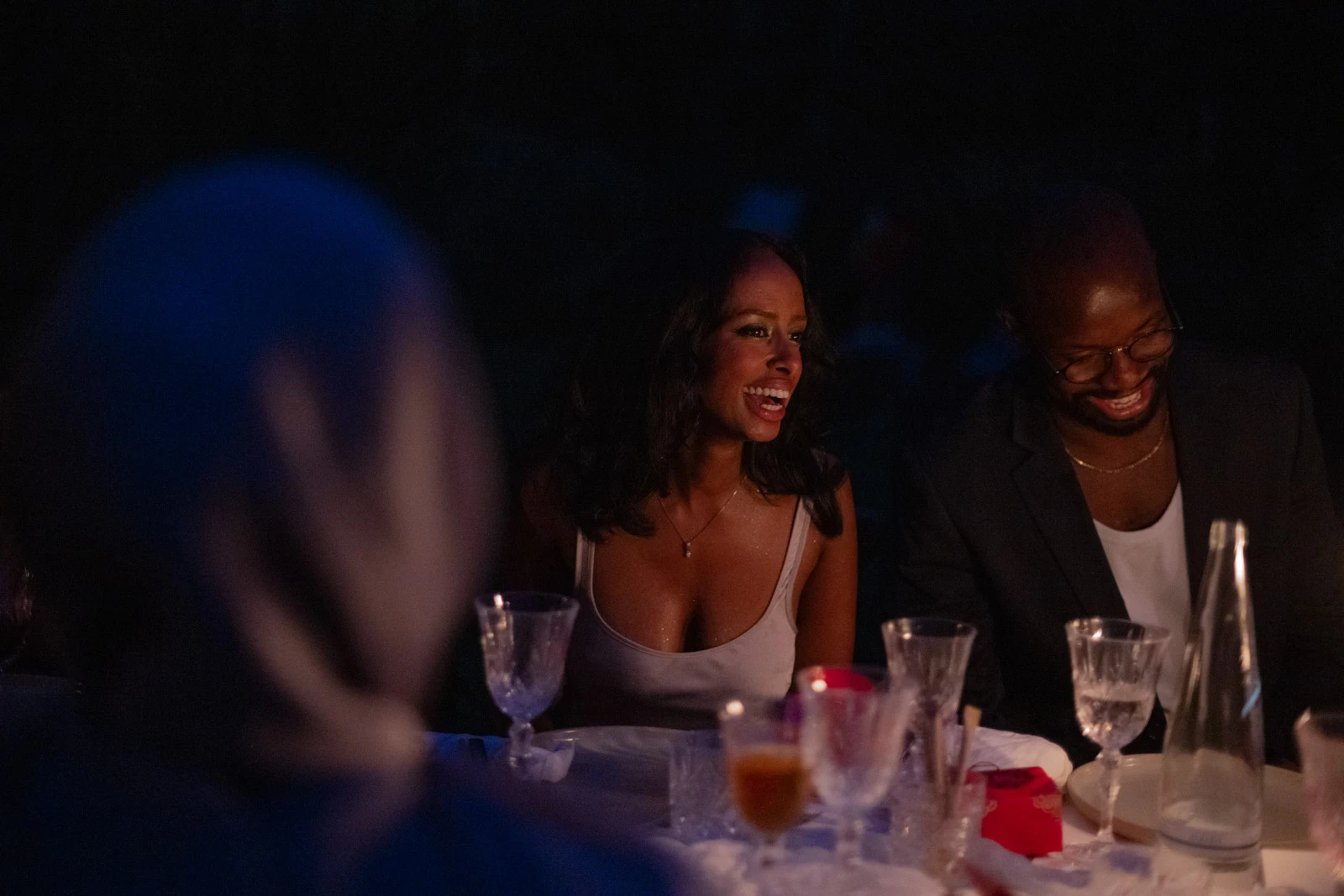 Guests seated at a wedding dinner table by candlelight in the evening