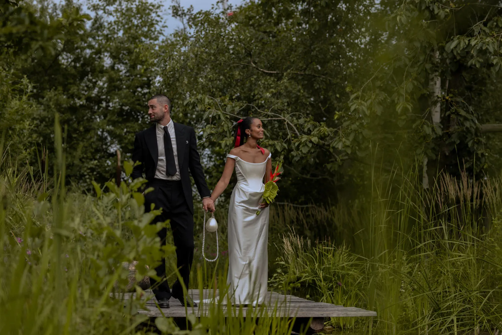 Wedding couple walking through tall grass in a green garden landscape