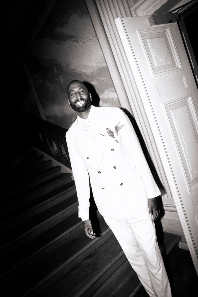 Groom in a white suit standing on a staircase in a historic building