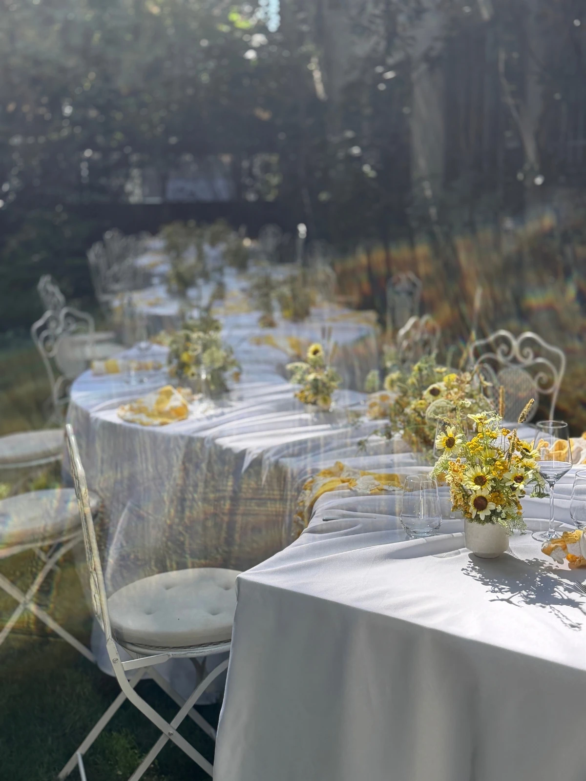 Lange gedeckte Tafel im Garten mit Blumenarrangements