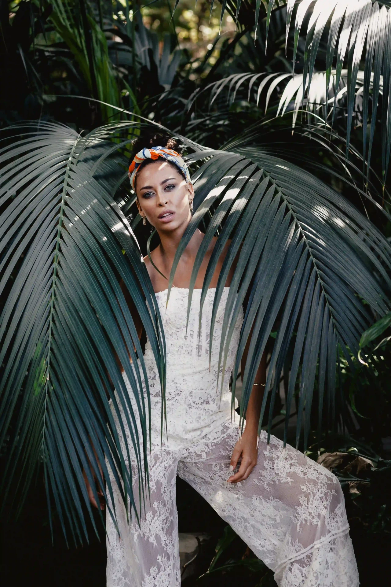 Bride in a lace wedding dress surrounded by large tropical leaves