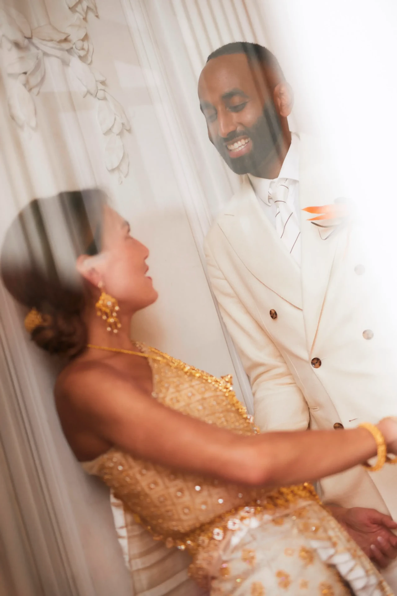 Groom in a white suit being embraced by a woman
