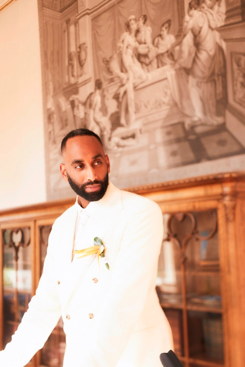 Groom in a white suit standing in a historic interior