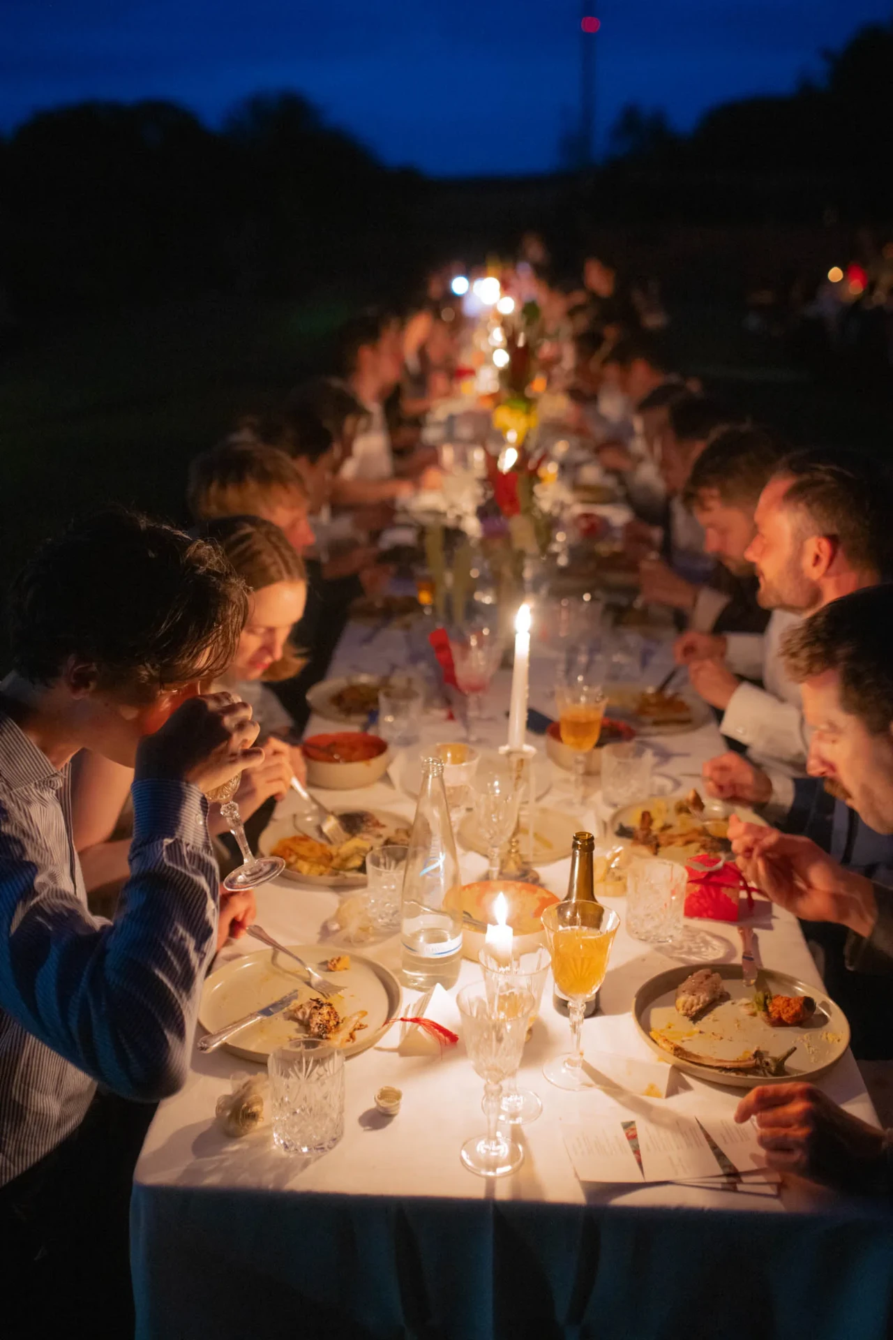 Long illuminated wedding table at an outdoor dinner at night