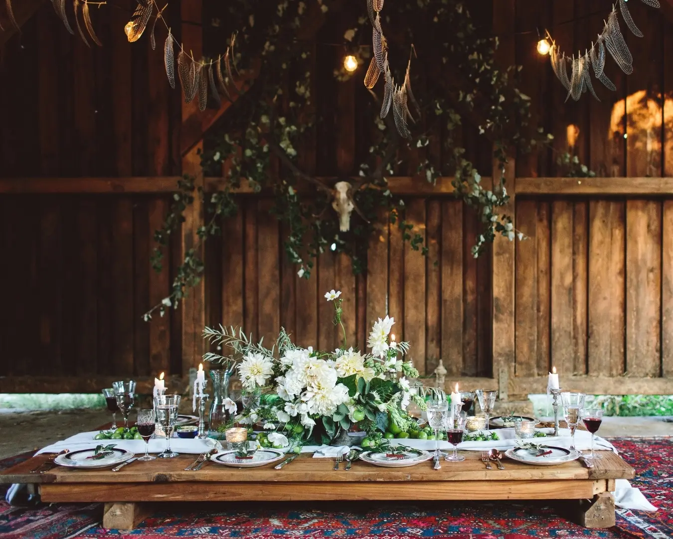 Wedding table with white flowers and candles against a rustic wooden wall