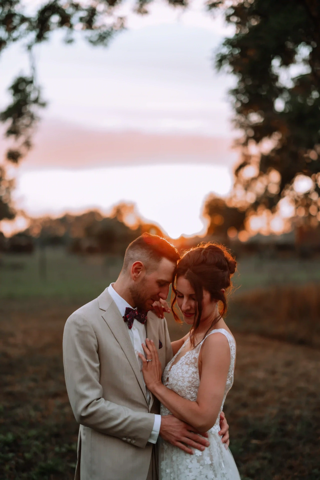 Bride and groom kissing outdoors at sunset