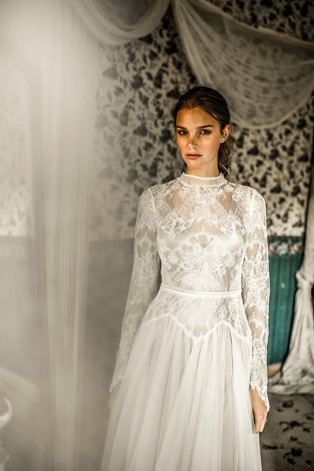 Braut im weißen Hochzeitskleid vor einer gemusterten Wand