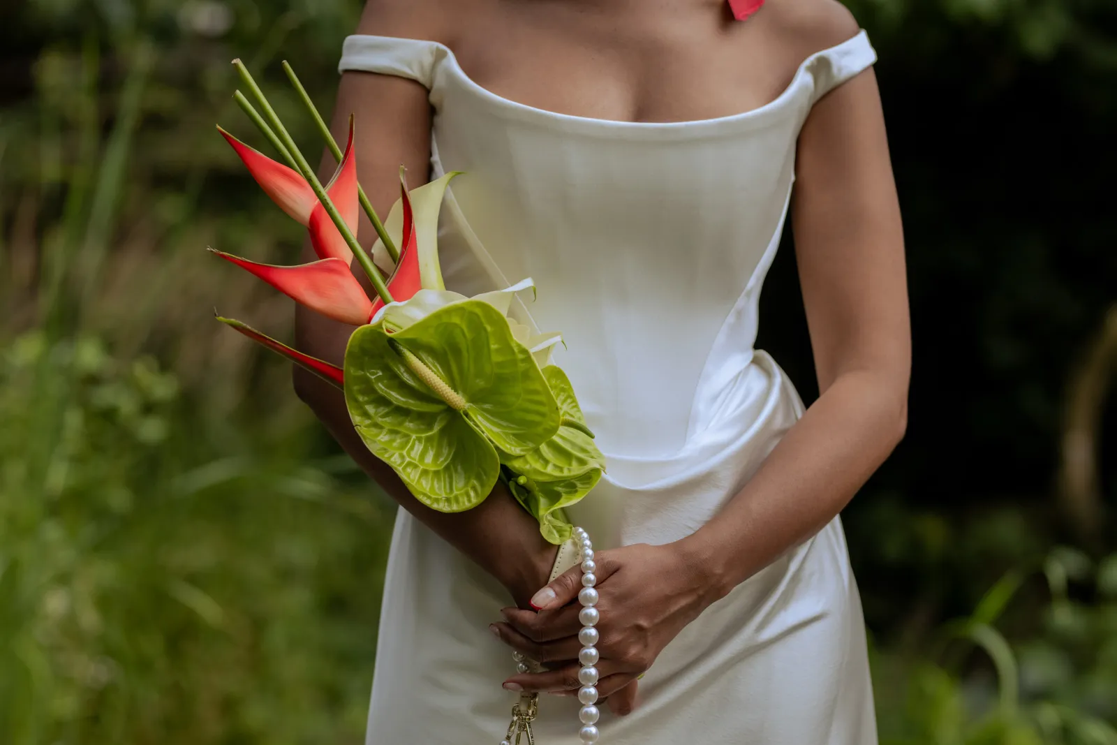 Bride holding a tropical bouquet in front of her white wedding dress