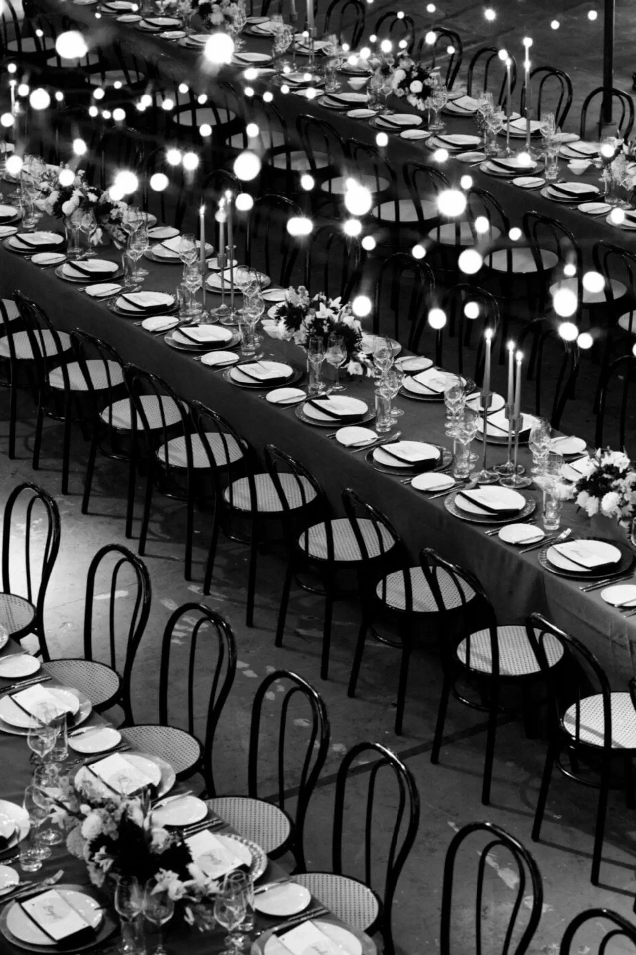 Black-and-white wedding table setting with a long dining table and glowing lights