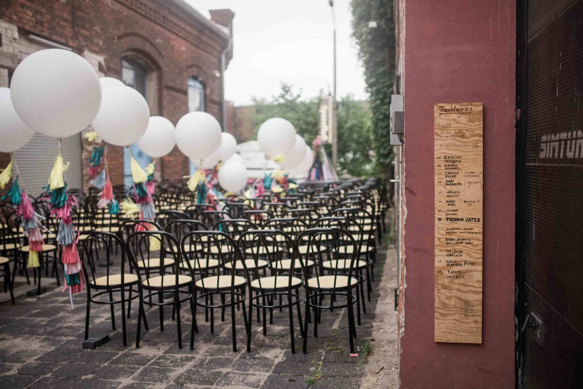 Long outdoor wedding table with black chairs and white balloons