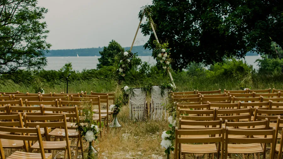White chairs arranged for an outdoor wedding ceremony in a garden