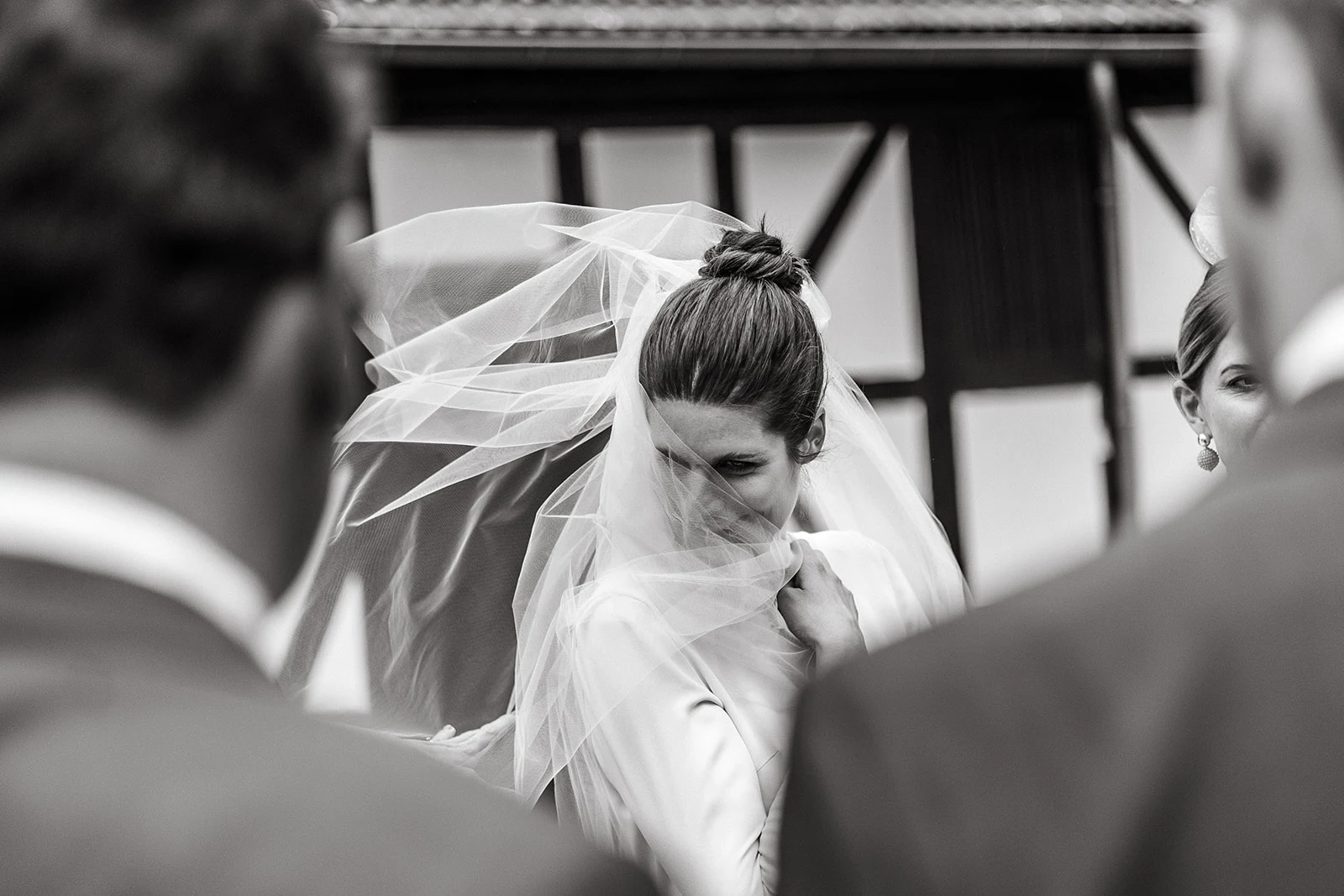 Bride with a veil surrounded by wedding guests, black-and-white photograph